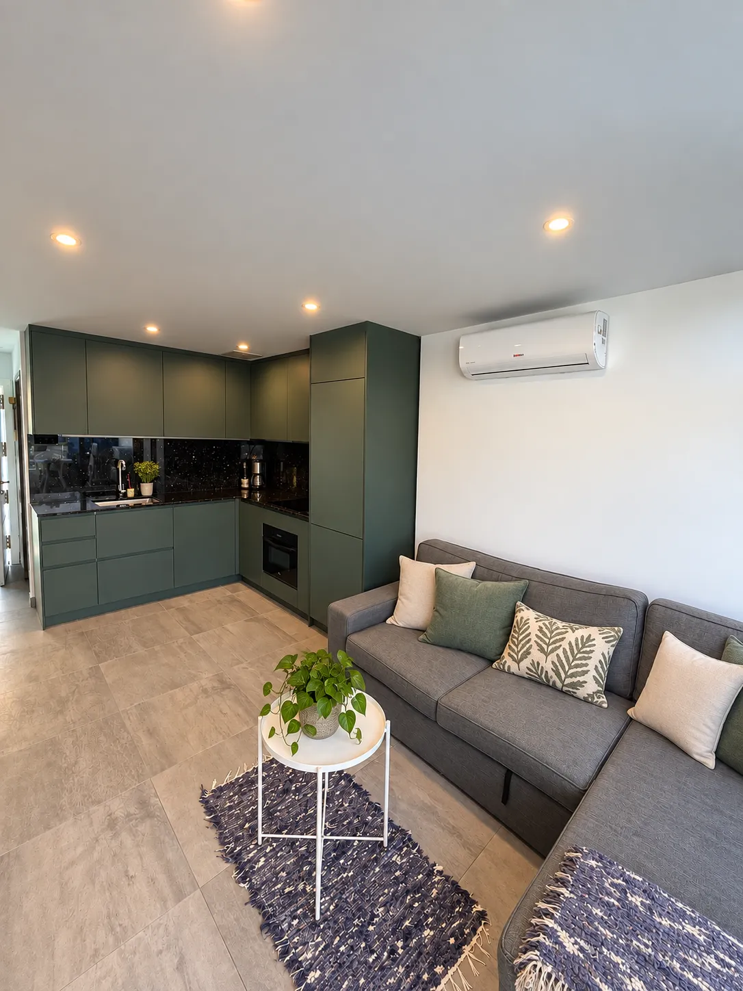 La cocina verde abierta al salón con un sofá gris